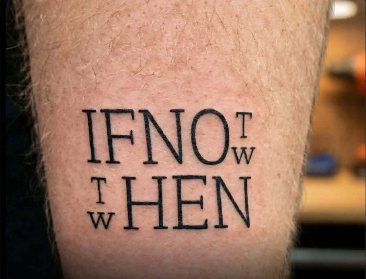 Photo of a tattoo with two lines of text.

The first line reads "if no", then the letters T and W vertically in a half size font.

The second line has the letters T and W vertically in a half size font again, followed by the word "hen".

Presumably the idea is to reuse text so it reads "if not now, then when?"